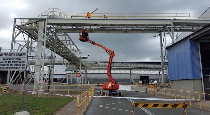 Electrician on red excavator  — 7E Integrated Services In Bolwarra Heights NSW