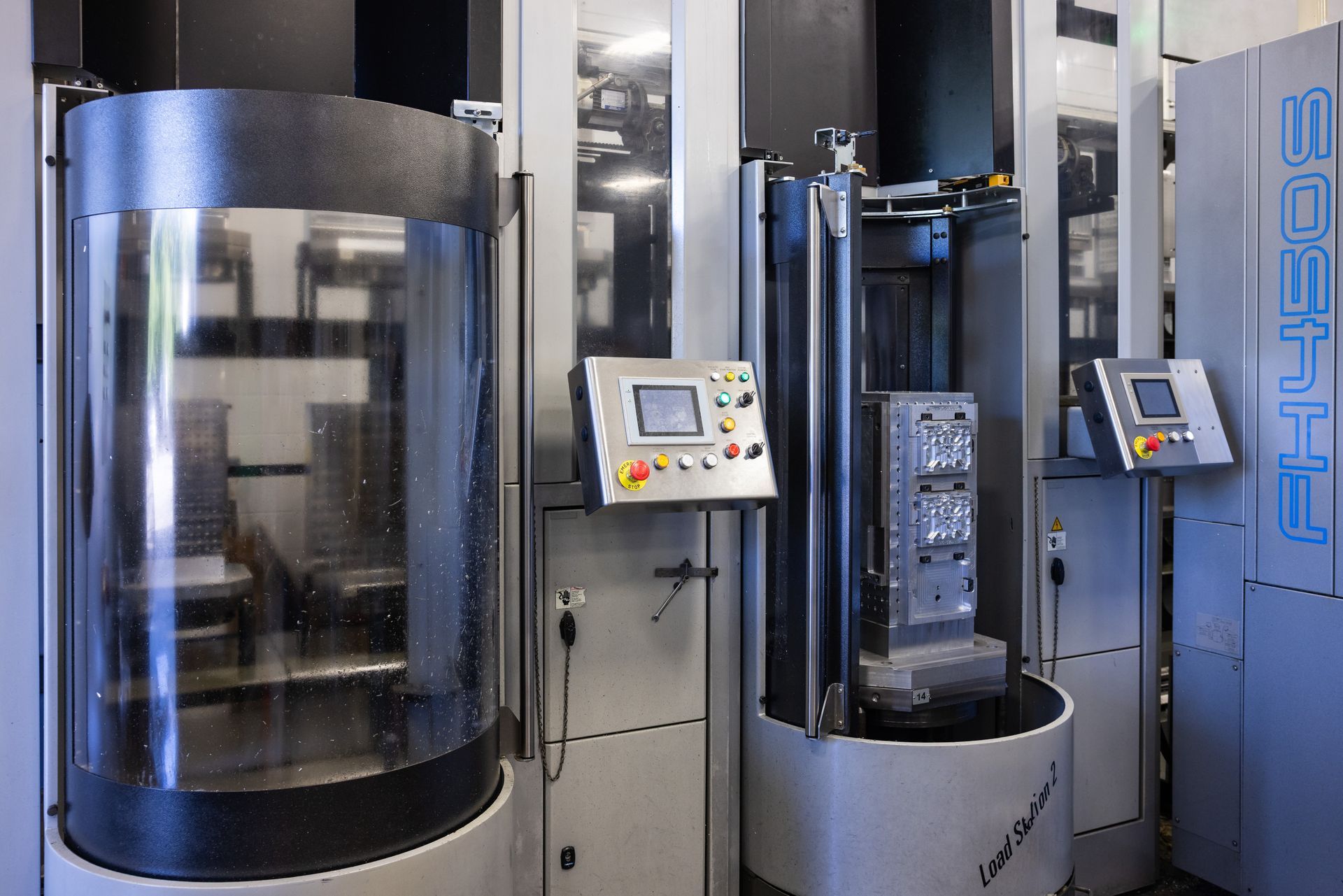 Industrial machinery in a workshop setting, with control panels and protective enclosures.