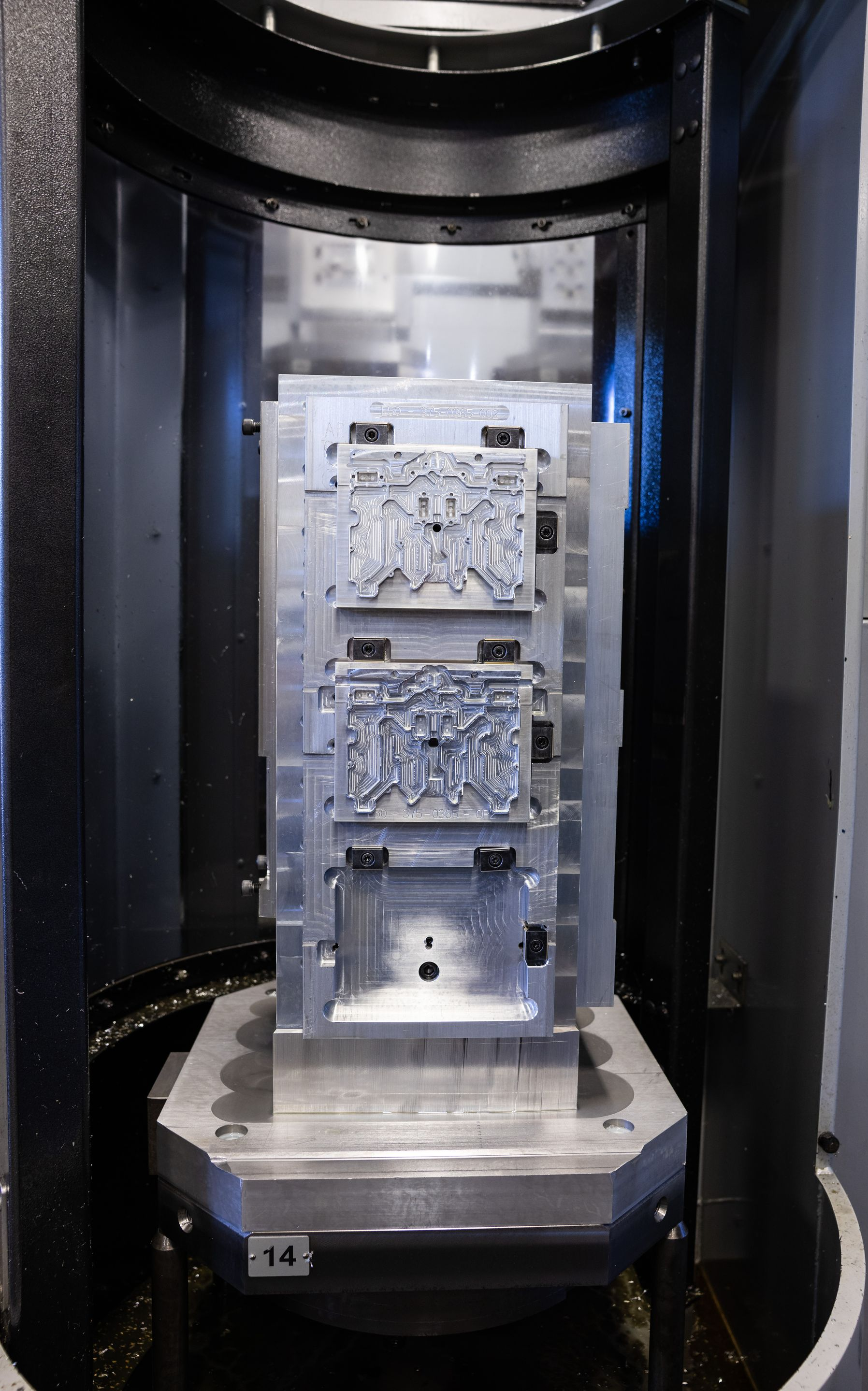 A CNC milling machine with a metal mold, showing intricate patterns and precise machining.