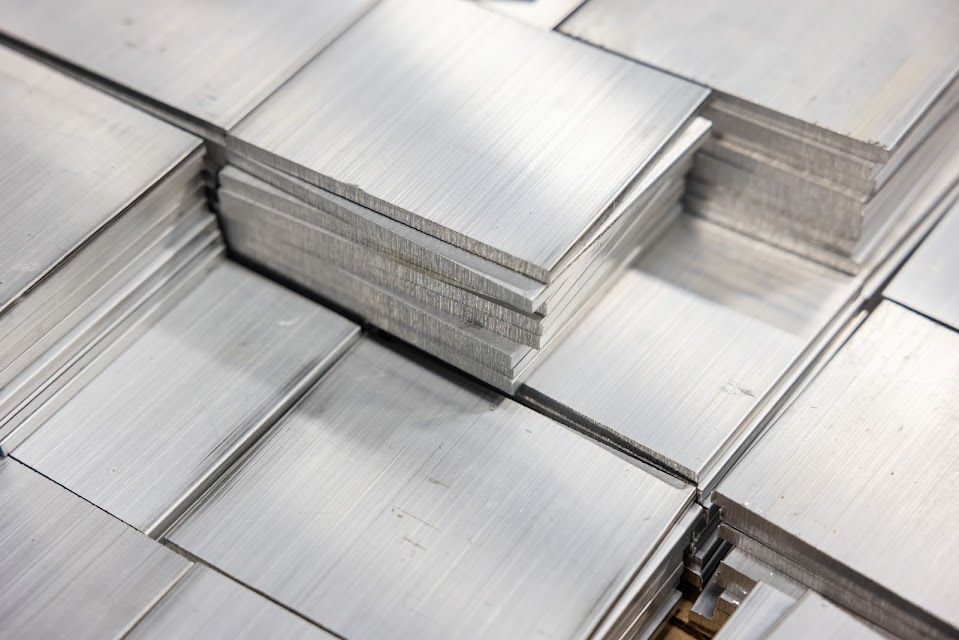 Stacks of square aluminum metal sheets, showing the edges and brushed surface finish.