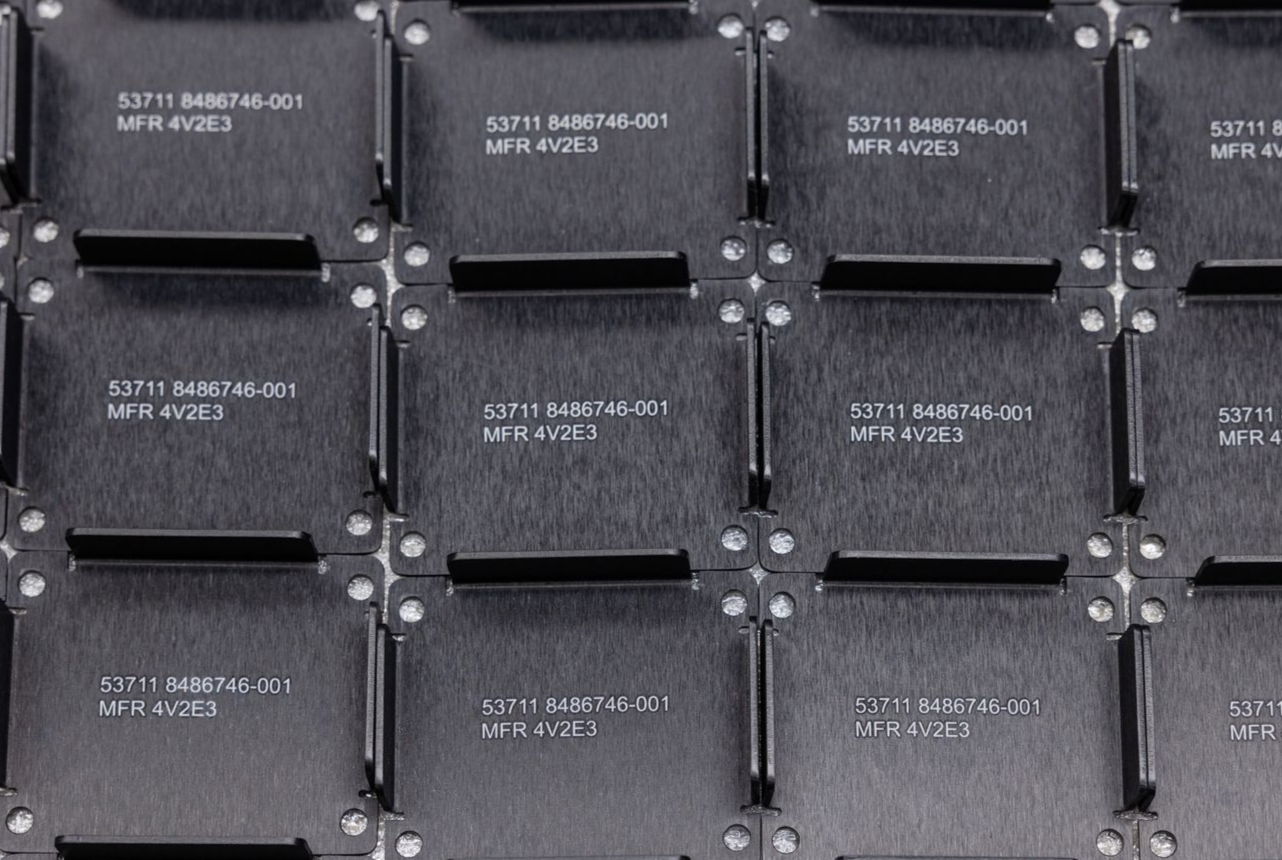 Close-up of a grid of metal rectangles with imprinted text and small rivets at the corners.