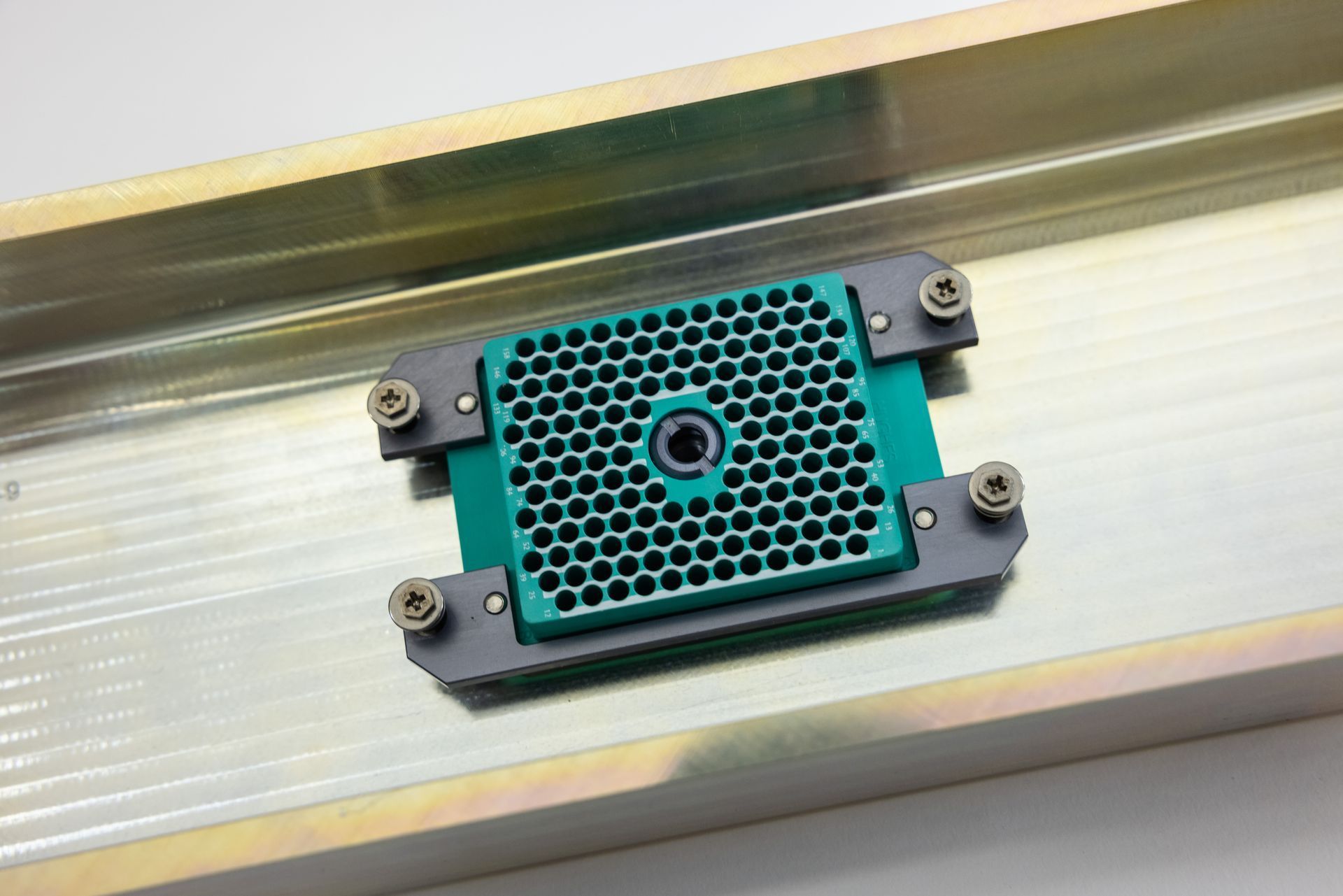 Green electronic component with honeycomb pattern, mounted in a metal tray.