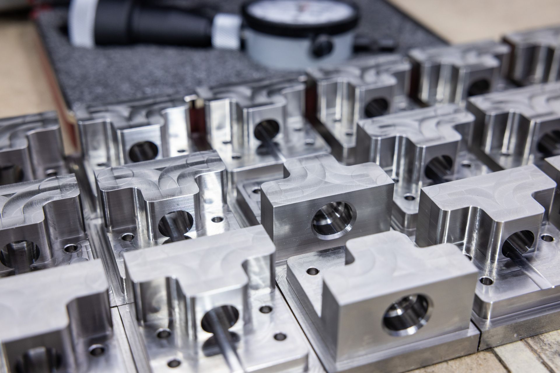 Close-up of a series of machined metal parts, likely for industrial use, arranged on a surface with measuring tools in the background.