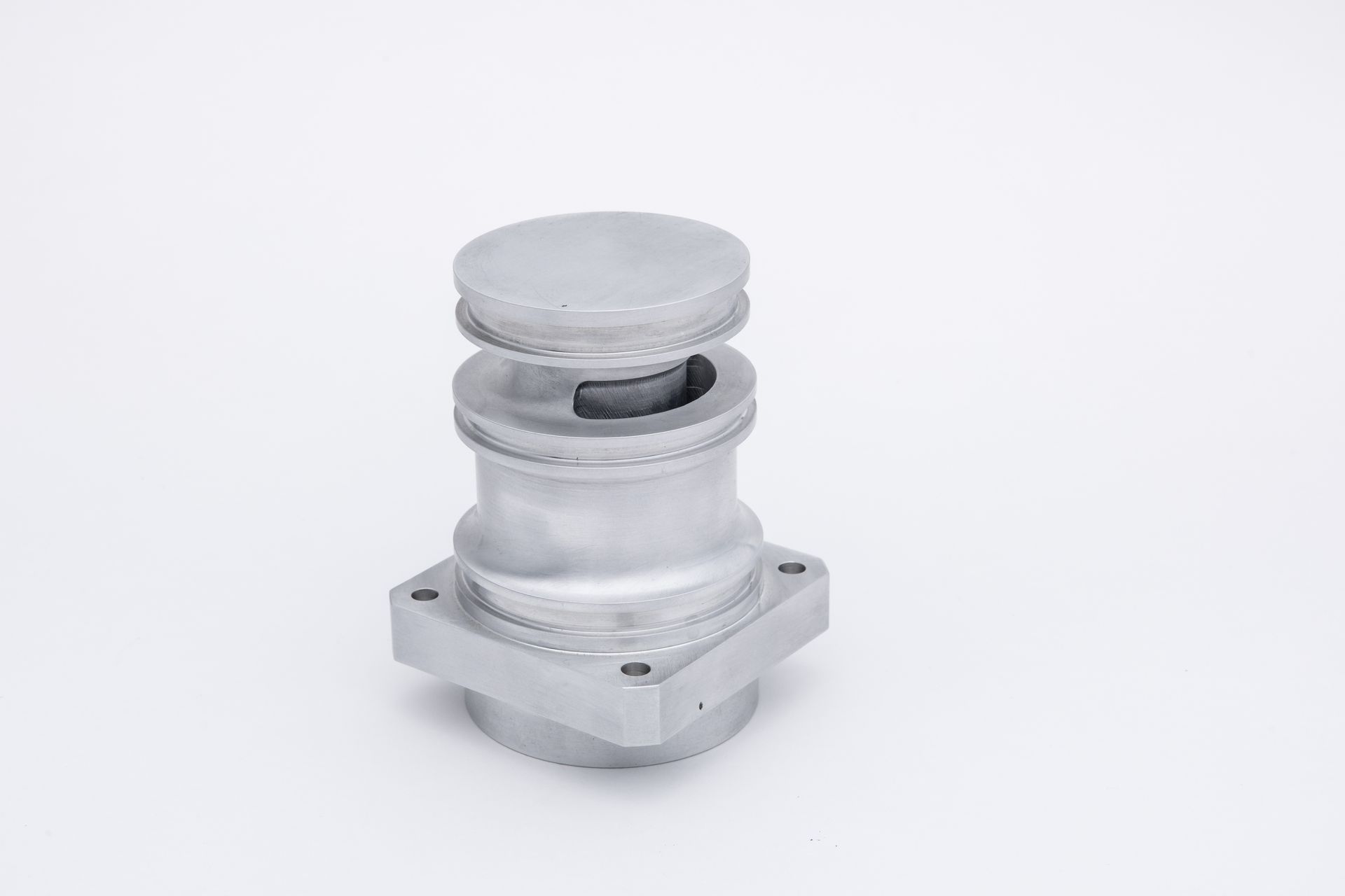 Silver industrial component with a square base, cylindrical body, and a circular top.