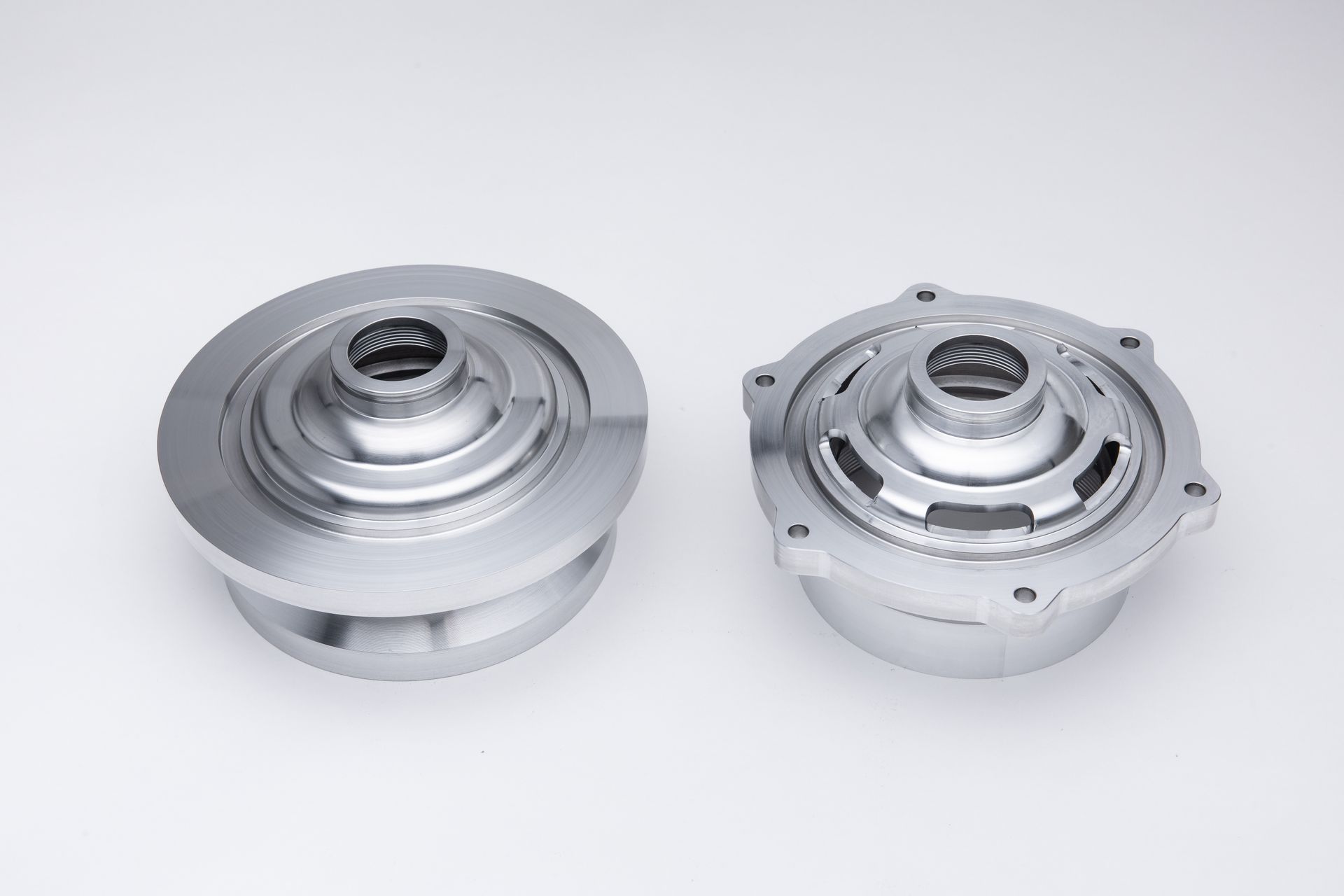 Two silver machined metal parts on a white background, likely mechanical components.