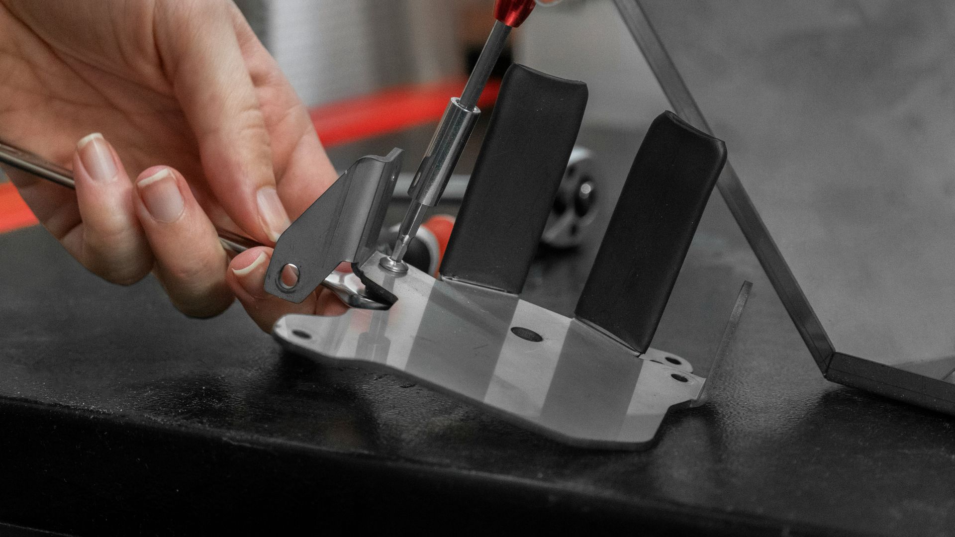 Hand holding a knife in a sharpening fixture, on a black surface.