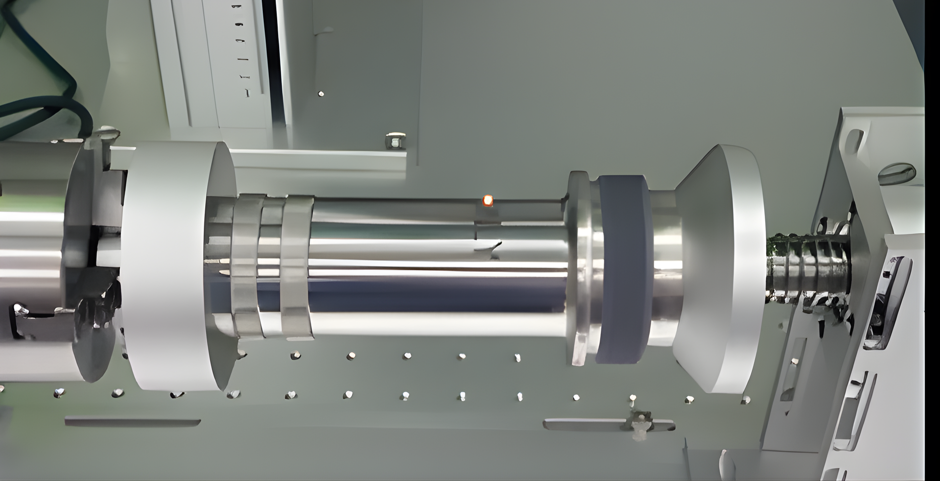 Silver cylindrical machine component with bands and a screw mechanism.