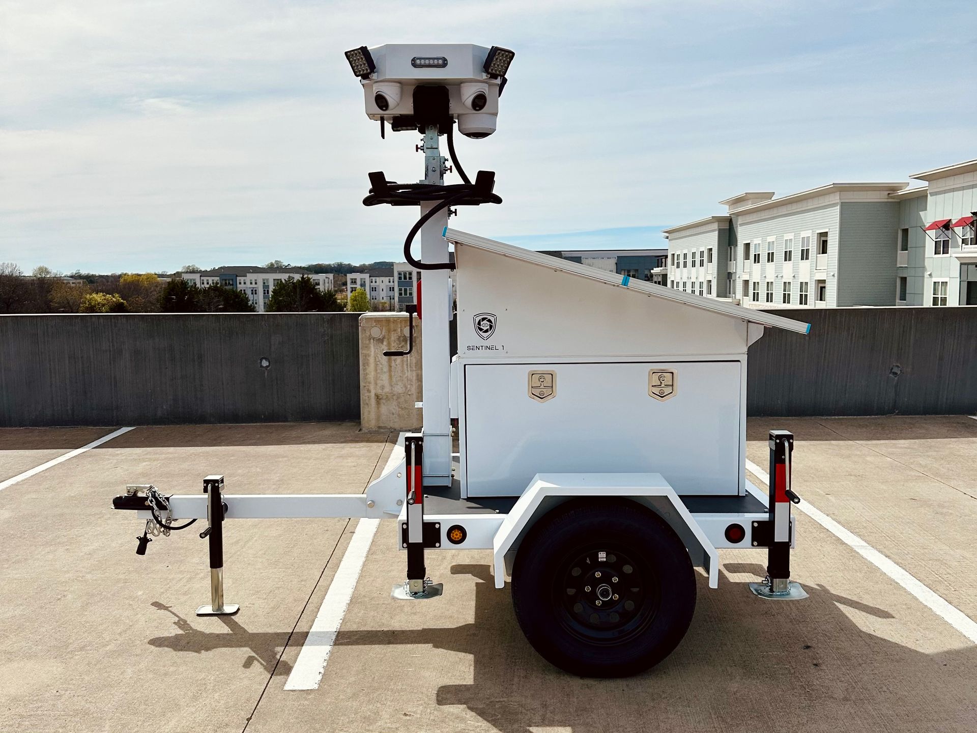 A trailer with a camera on top of it is parked in a parking lot.