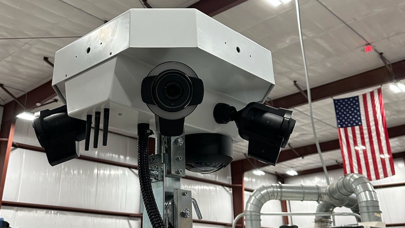 A camera is hanging from the ceiling of a building next to an american flag.