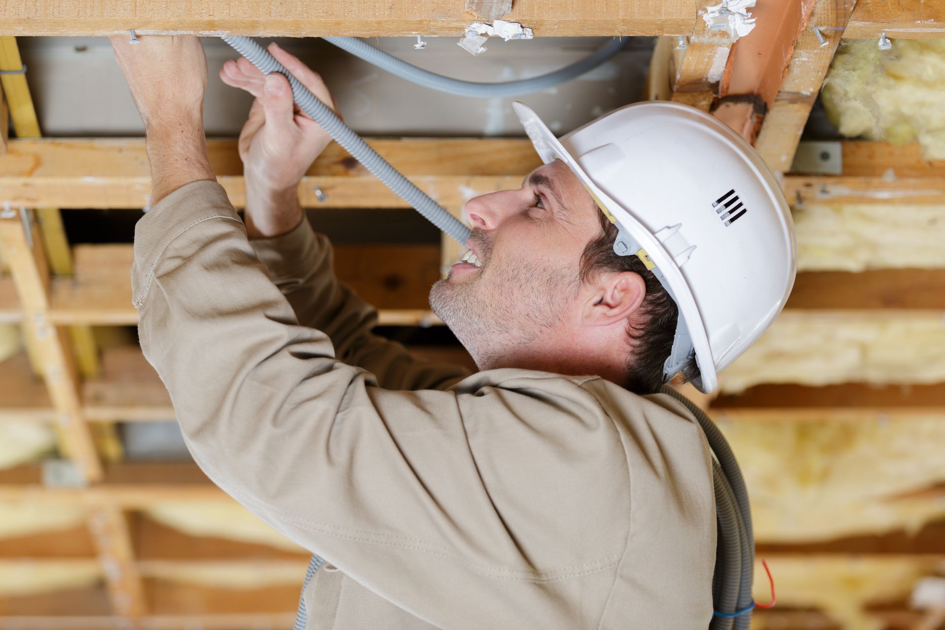 Builder passing cables through the ceiling joists. Builder passing cables through the ceiling joists.