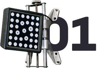 Close-up of a wheel alignment target with black background and white dots, mounted on a silver frame. | Greg's Garage