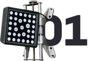 Close-up of a wheel alignment target with black background and white dots, mounted on a silver frame. | Greg's Garage