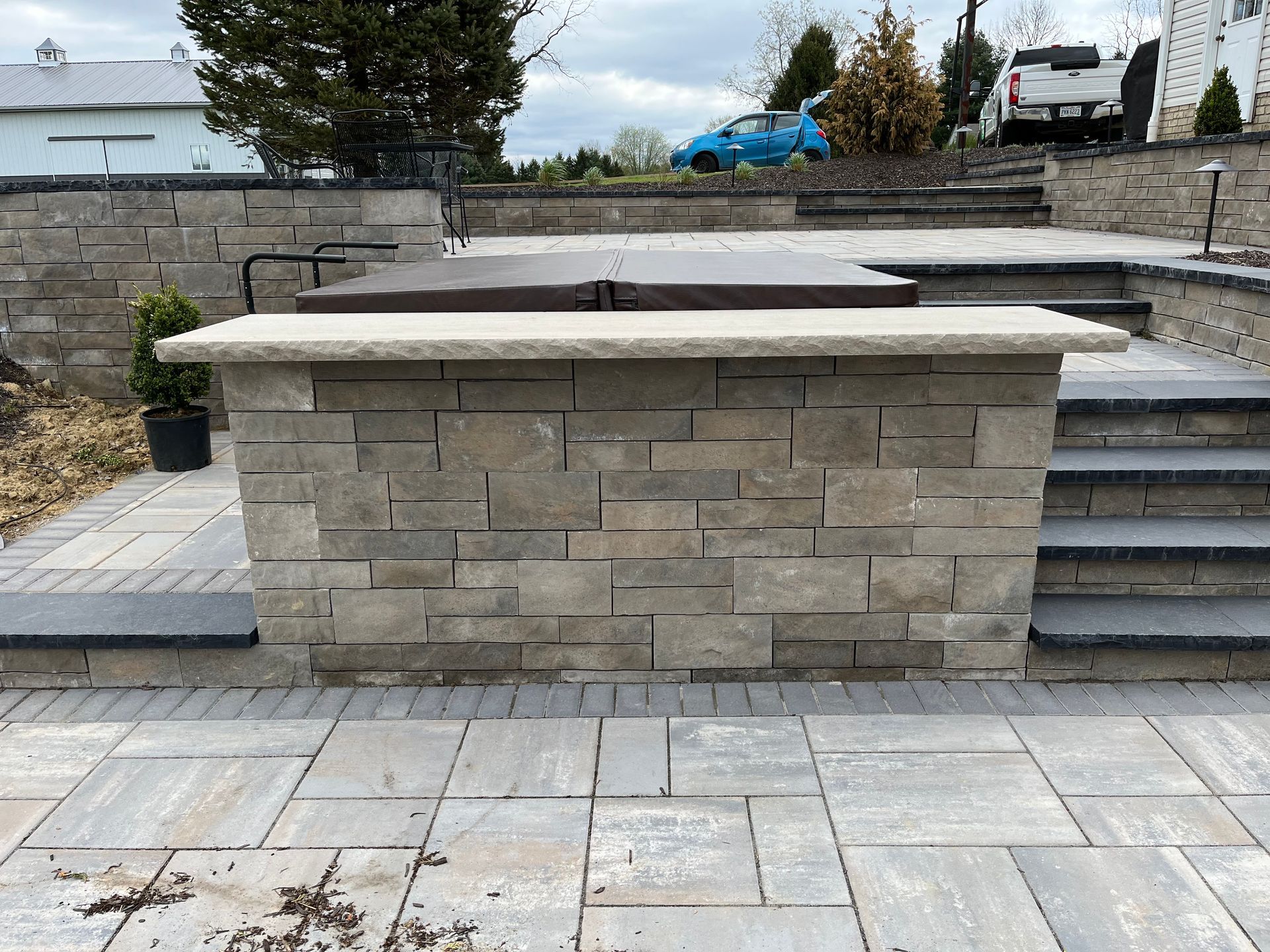 Stone outdoor bar with steps, patio, and hot tub in background.