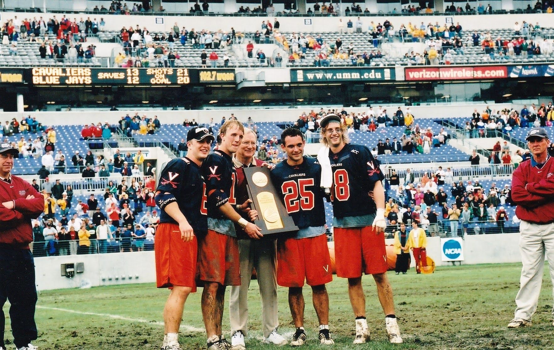 2003 National Champions University of Virginia (UVA) Lacrosse team Captains: Ned Bowen, Chris Rotelli, Trey Whitty, AJ Shannon in orange/navy uniforms celebrating a championship with the National Championship trophy on M&T Bank stadium.