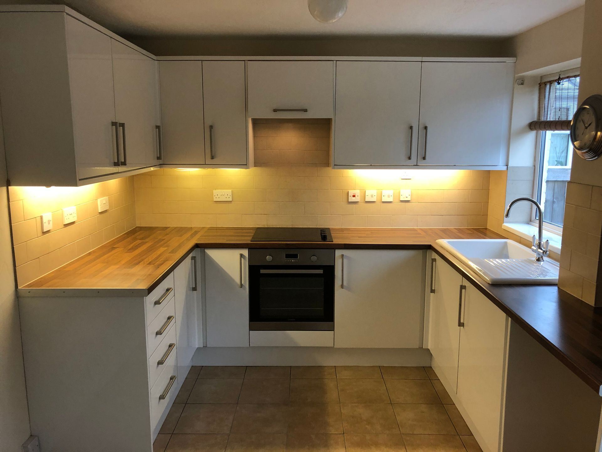 A kitchen with white cabinets and wooden counter tops