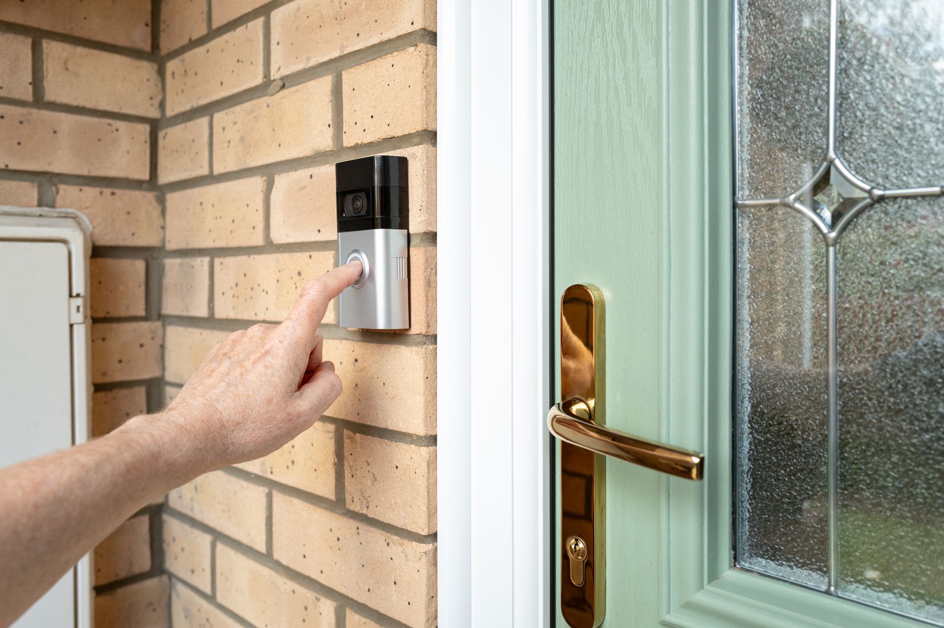 A person is pressing a button on a doorbell.