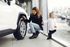 A woman and a child are looking at a car in a showroom.