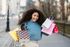 A woman is holding a bunch of shopping bags and smiling.