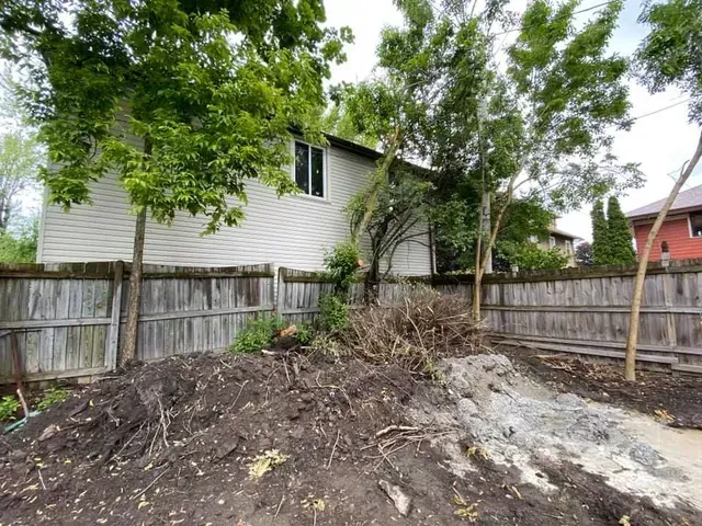 A house with a wooden fence and a pile of dirt in front of it.