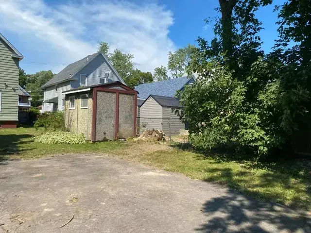 A shed is in the backyard of a house.