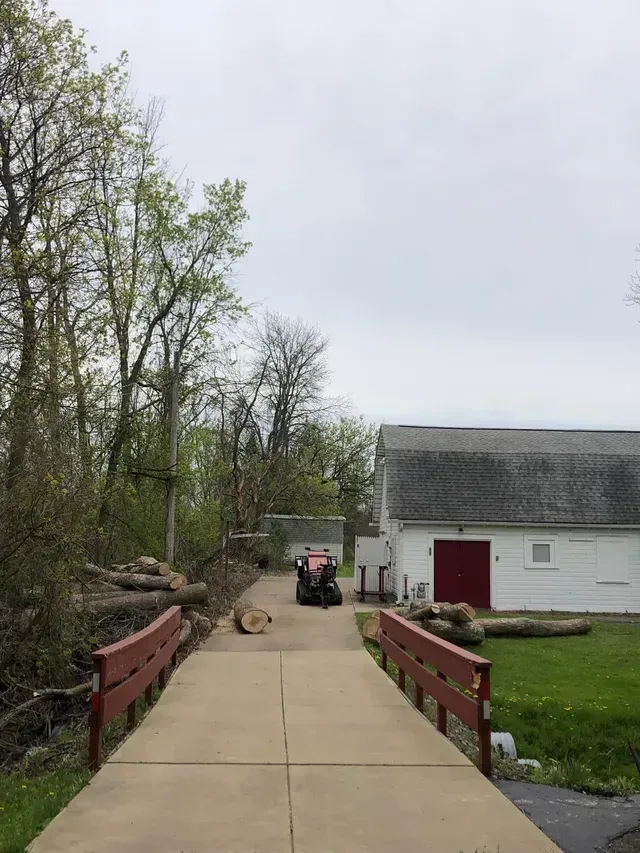 A red atv is parked on the side of a road next to a barn.