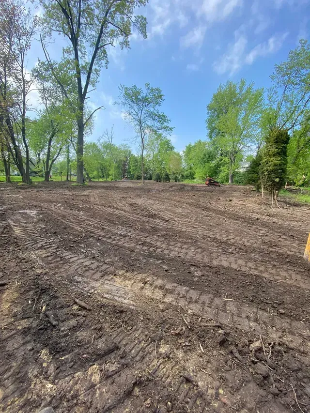 A dirt field with trees in the background on a sunny day.