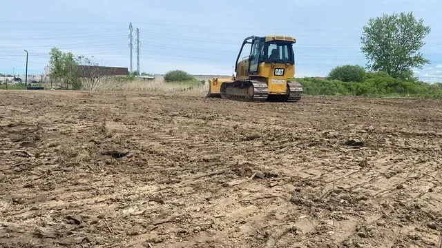 A bulldozer is driving through a muddy field.