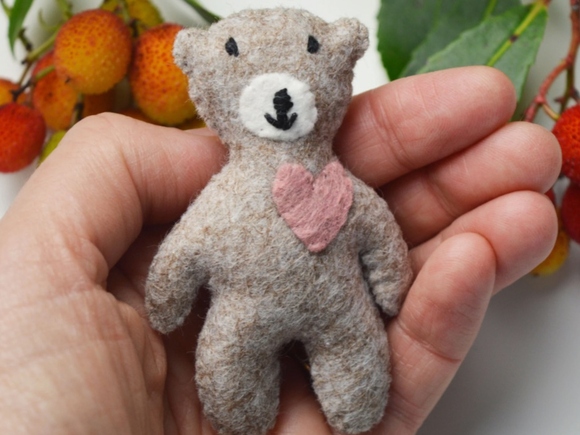 A mini felt bear held in a hand, having been made from the free pattern offered by A Sewing Life when subscribing to the newsletter