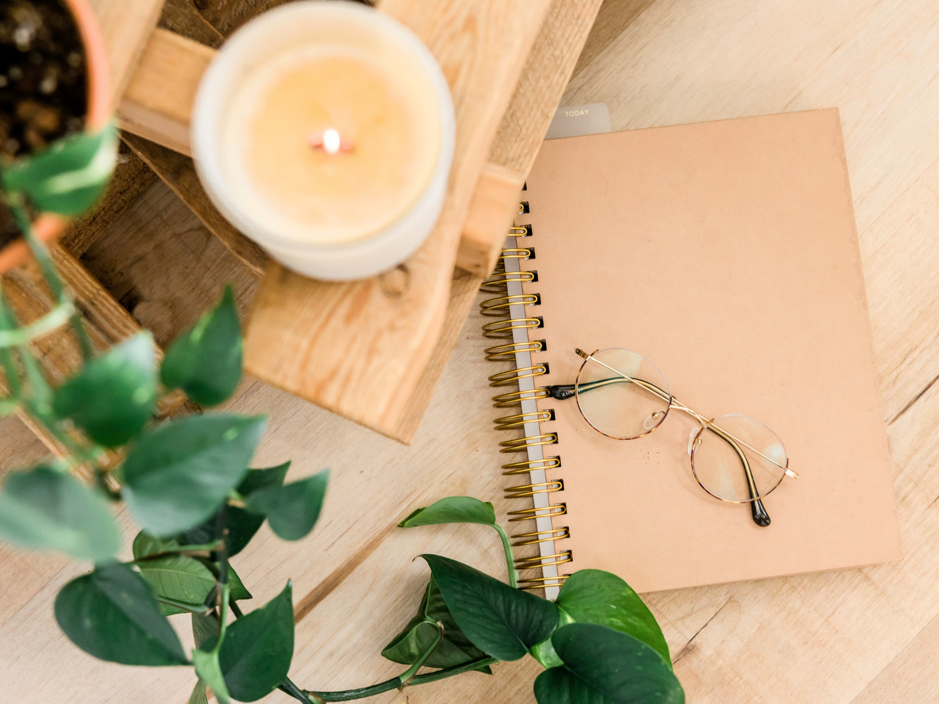 soft calming stationary, plants, a candle & a pair of glasses