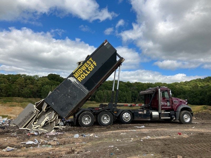 A dark maroon roll-off truck is tilted backward.