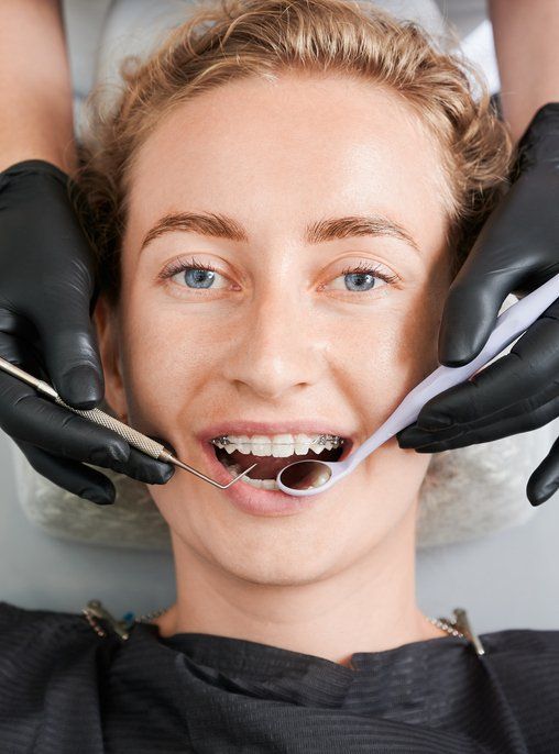 Dentist examining woman teeth with braces.