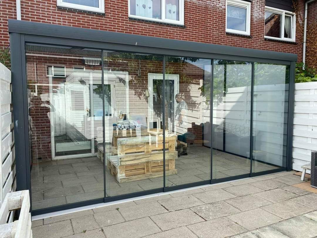 Een patio met glazen schuifdeuren en een bakstenen gebouw op de achtergrond.