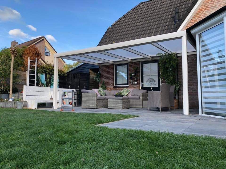Voor een huis bevindt zich een patio met een overkapping.