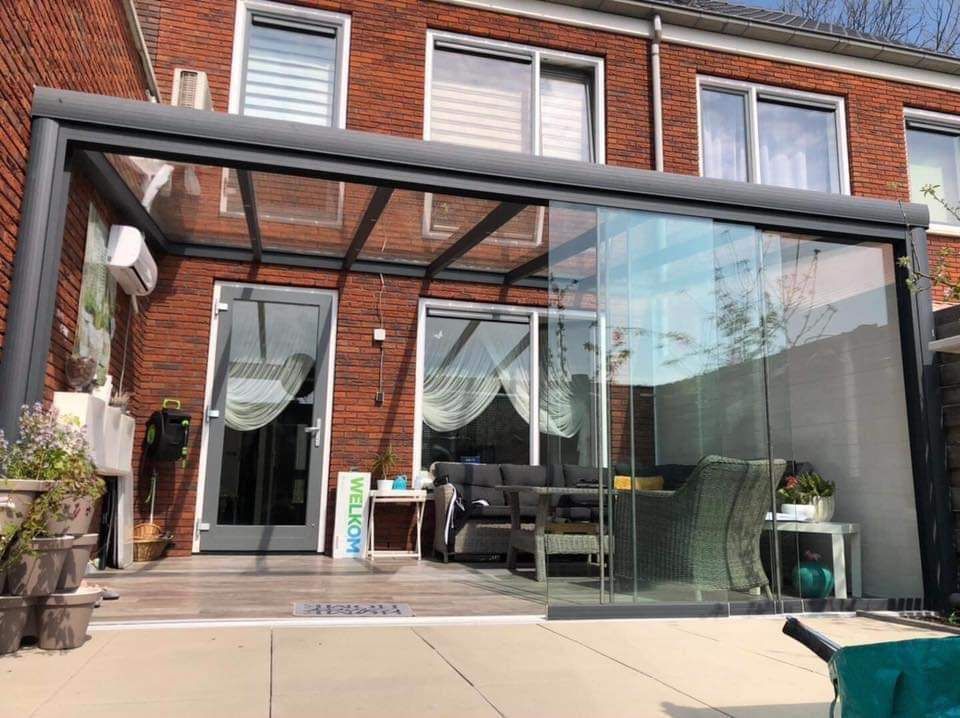 Een bakstenen huis met een glazen dak en glazen schuifdeuren.