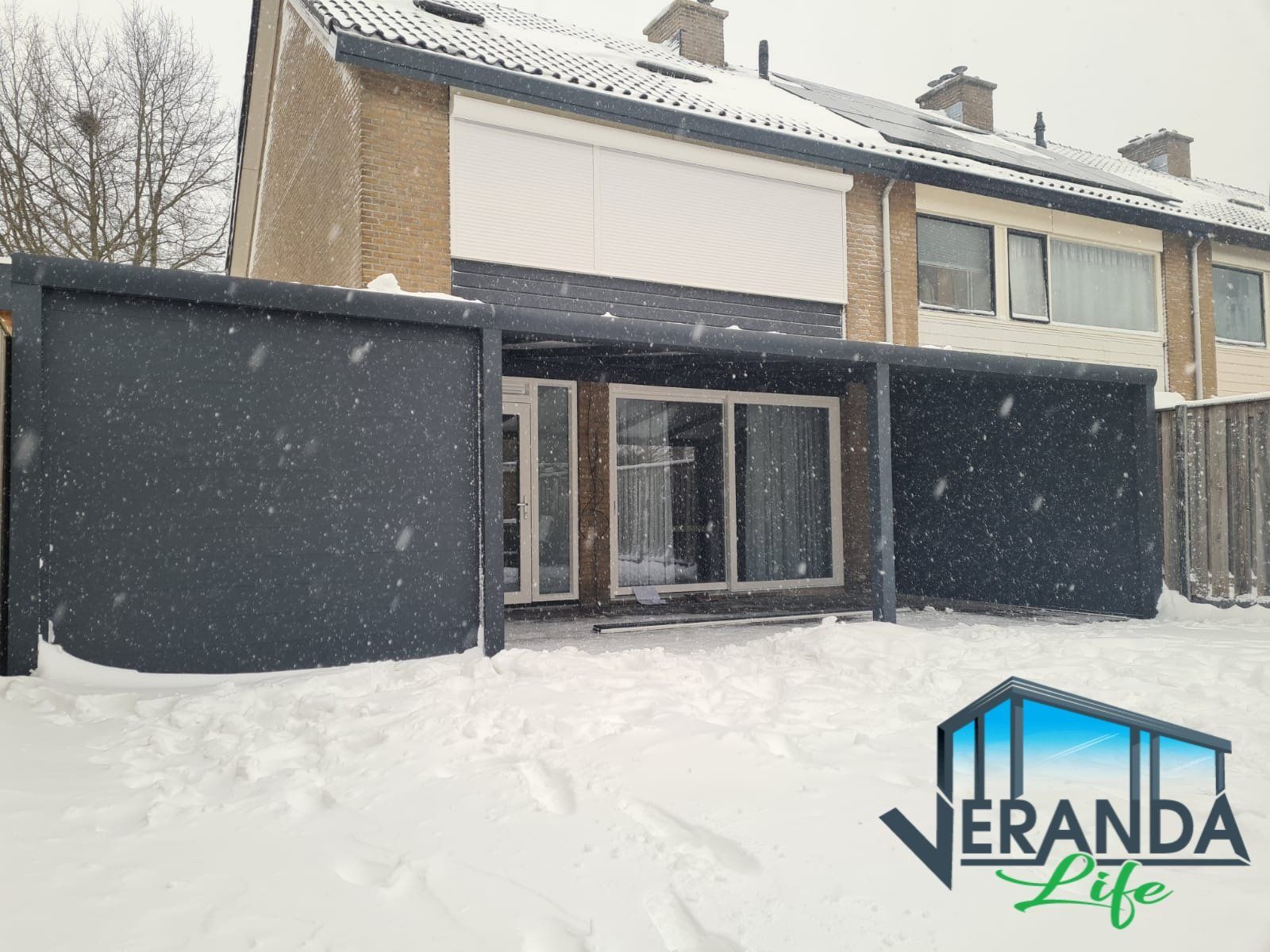 Een foto van een huis in de sneeuw met onderaan het veranda-leven geschreven