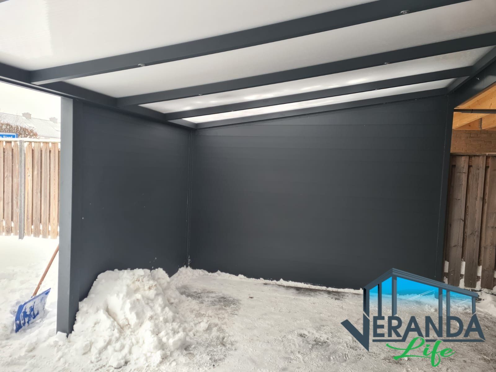 Een grote stapel sneeuw ligt onder een overdekte ruimte.