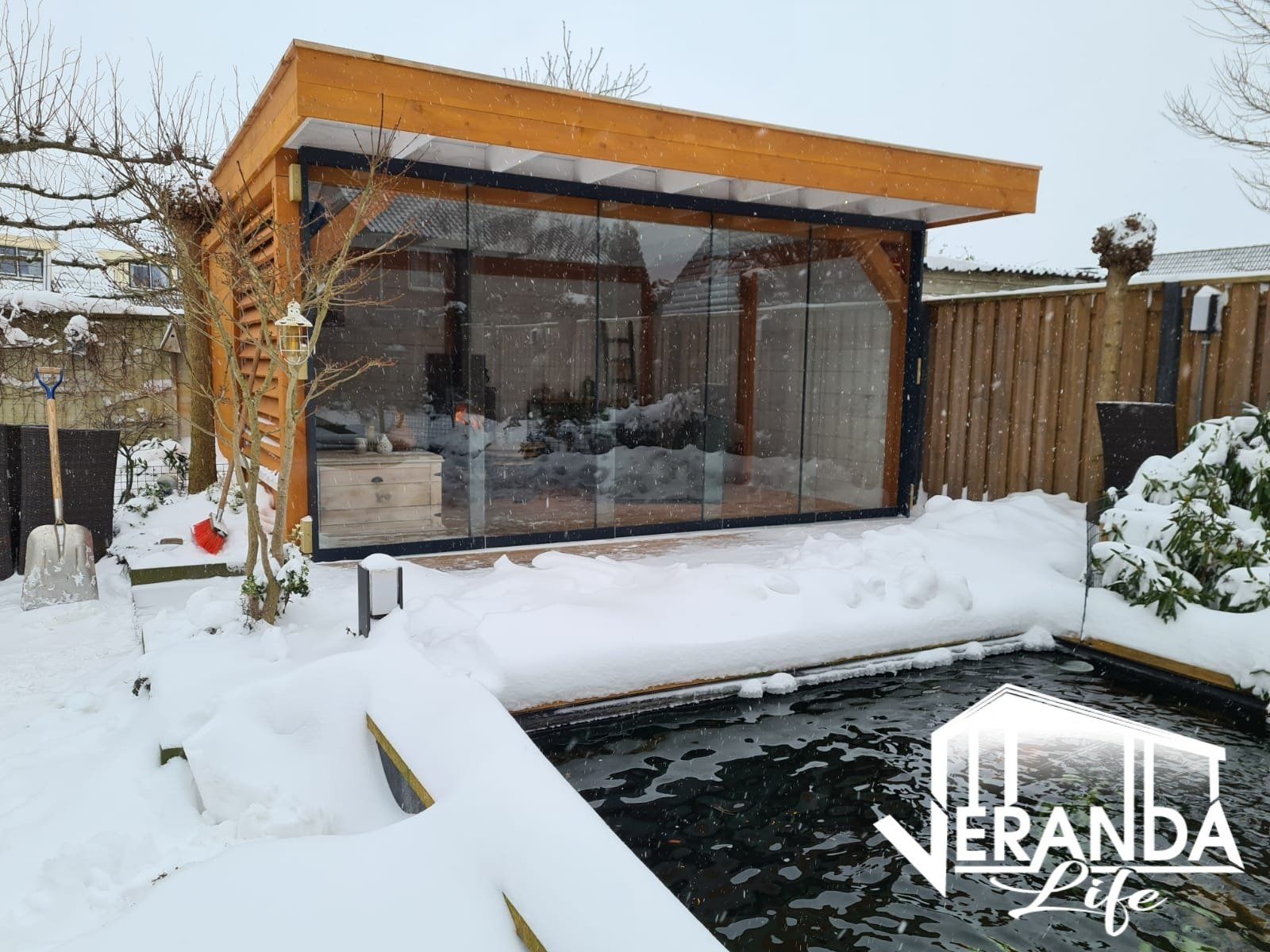 Een huis met een vijver ervoor is bedekt met sneeuw.