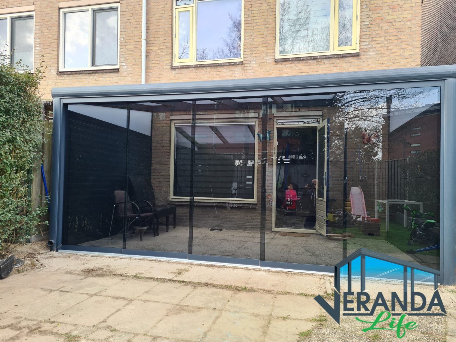 Een patio met glazen schuifdeuren en een bakstenen gebouw op de achtergrond.