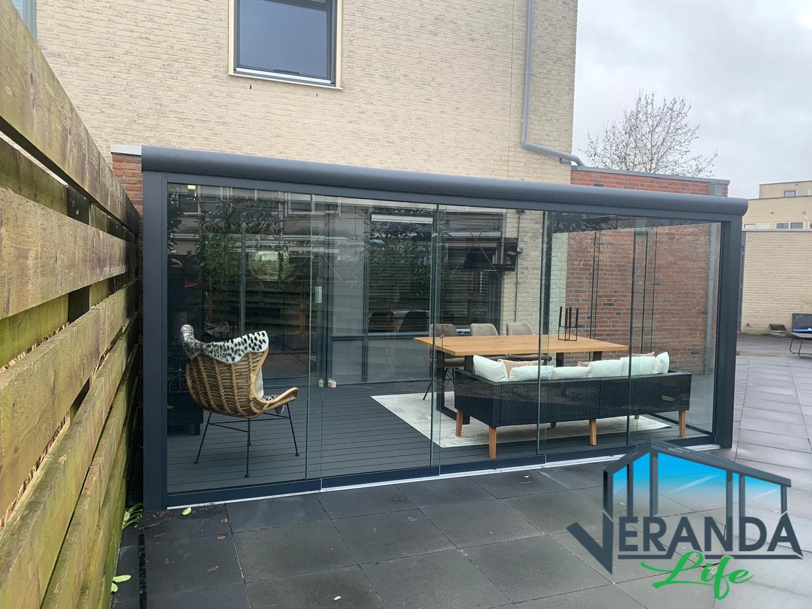 Een patio met een tafel en stoelen onder een glazen dak.