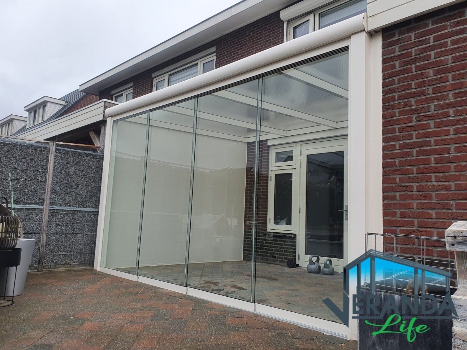 Een bakstenen huis met een glazen dak en glazen schuifdeuren.