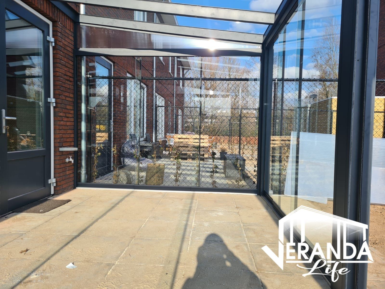 Een grote glazen kamer met een bakstenen gebouw op de achtergrond.