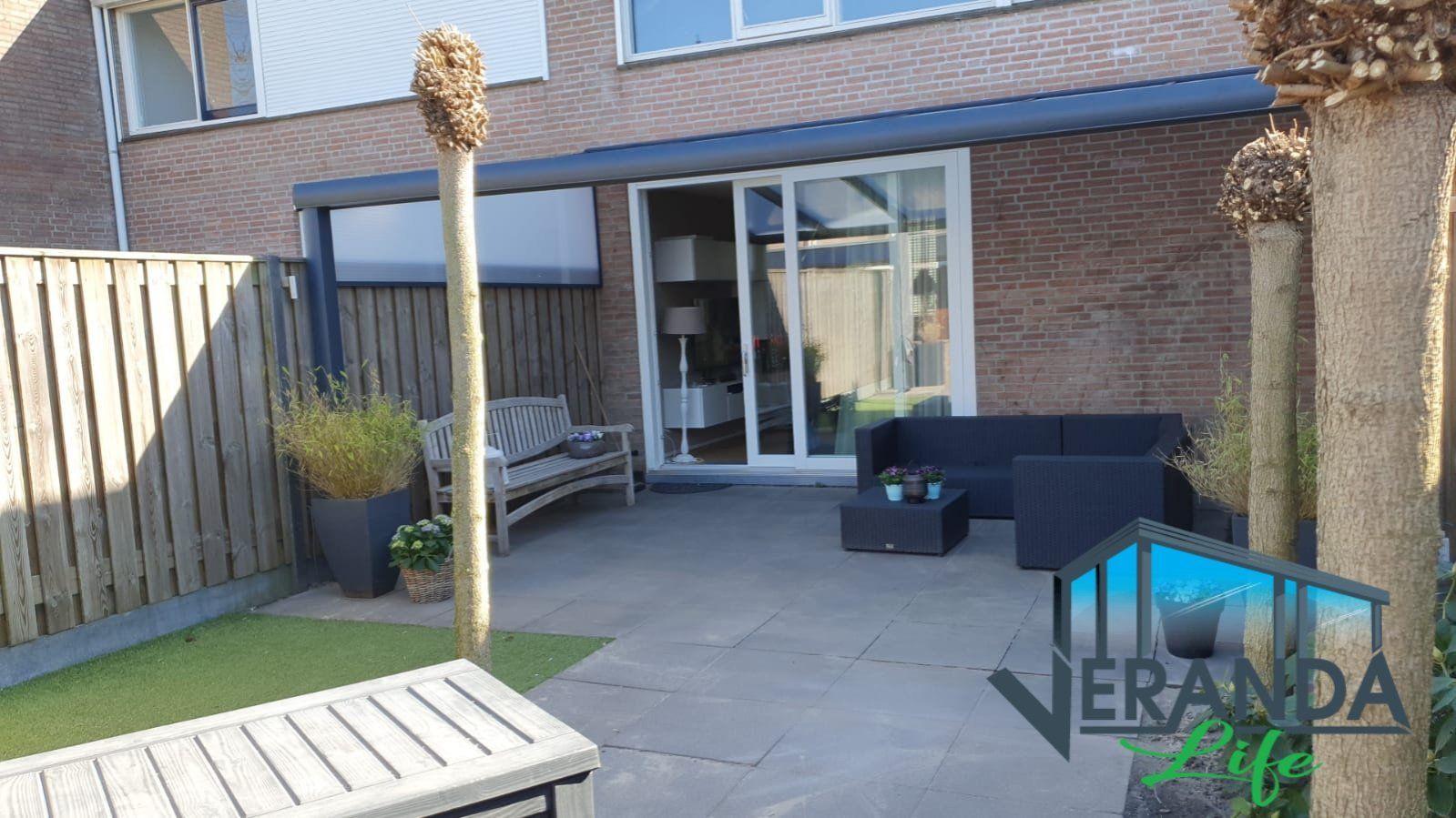 Een patio met een bank en een bank voor een huis.