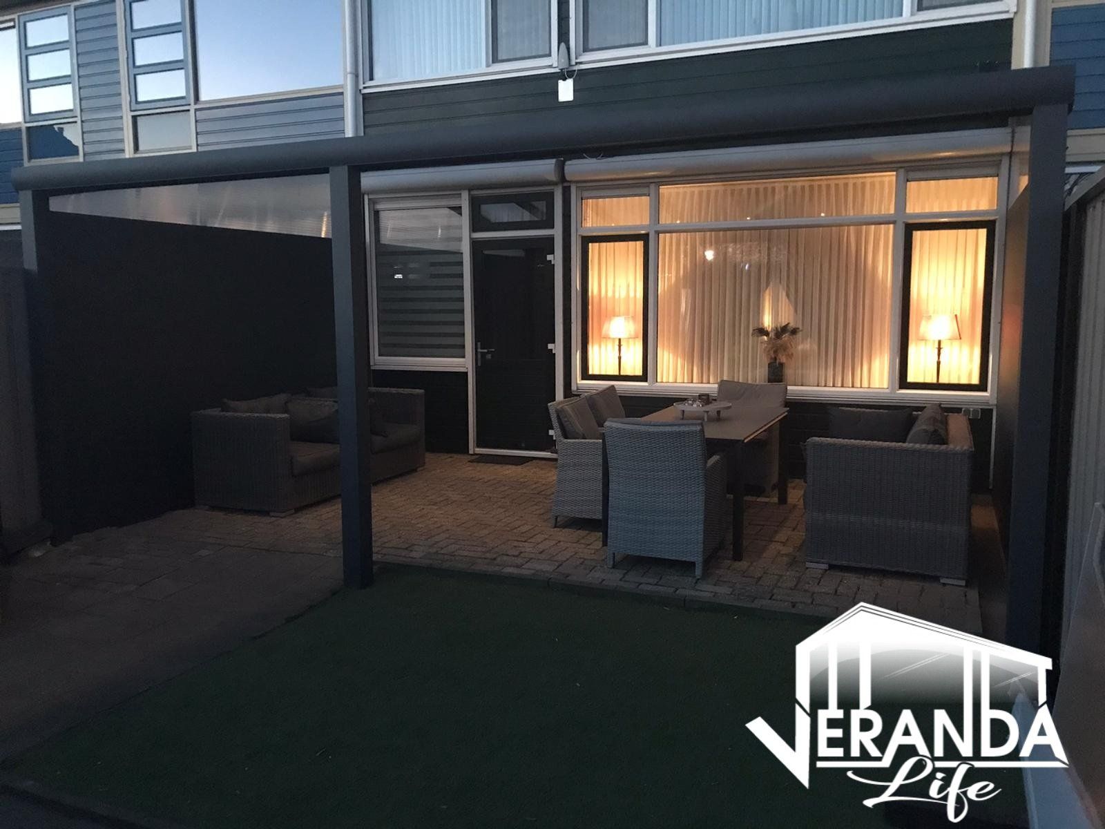 Een veranda met een tafel en stoelen voor een huis