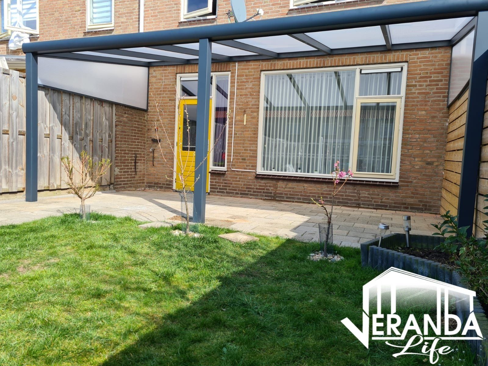 Er is een overdekt terras in de achtertuin van een huis.