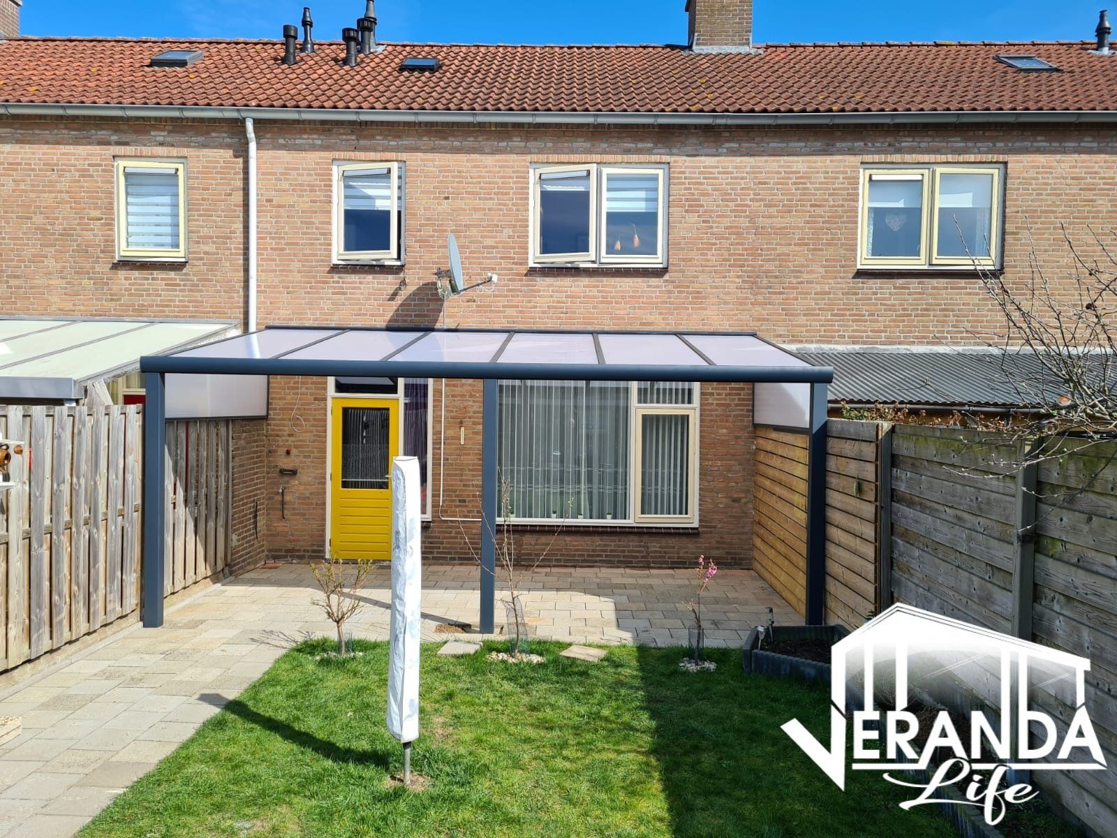 Een bakstenen huis met een overdekt terras in de achtertuin