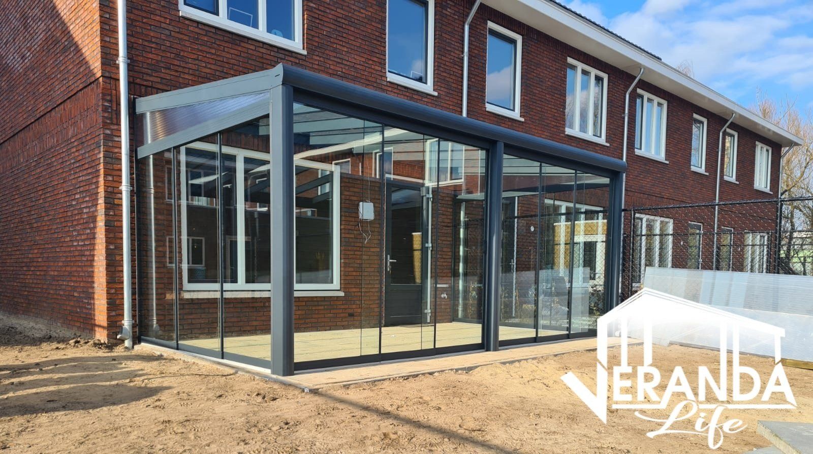 Een bakstenen gebouw met ervoor een grote glazen kamer.