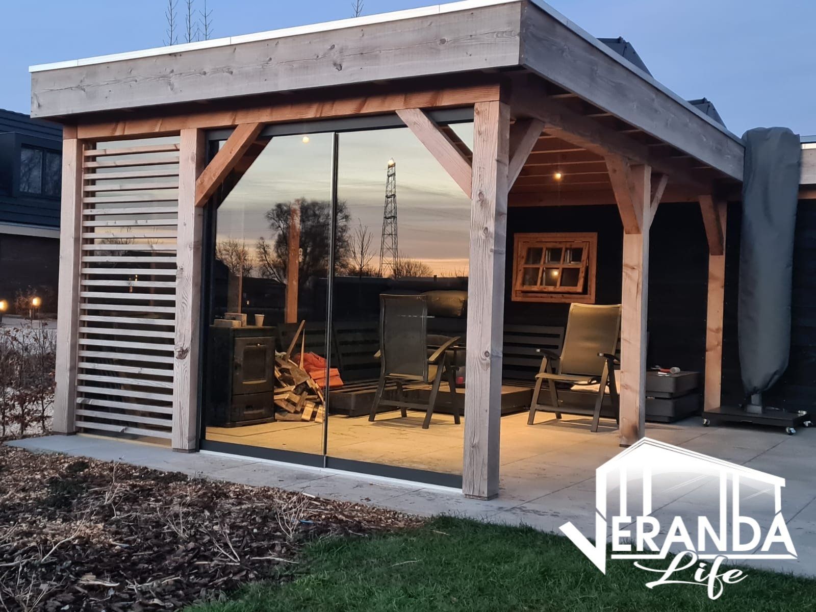 Een houten tuinhuisje met glazen schuifdeuren en stoelen