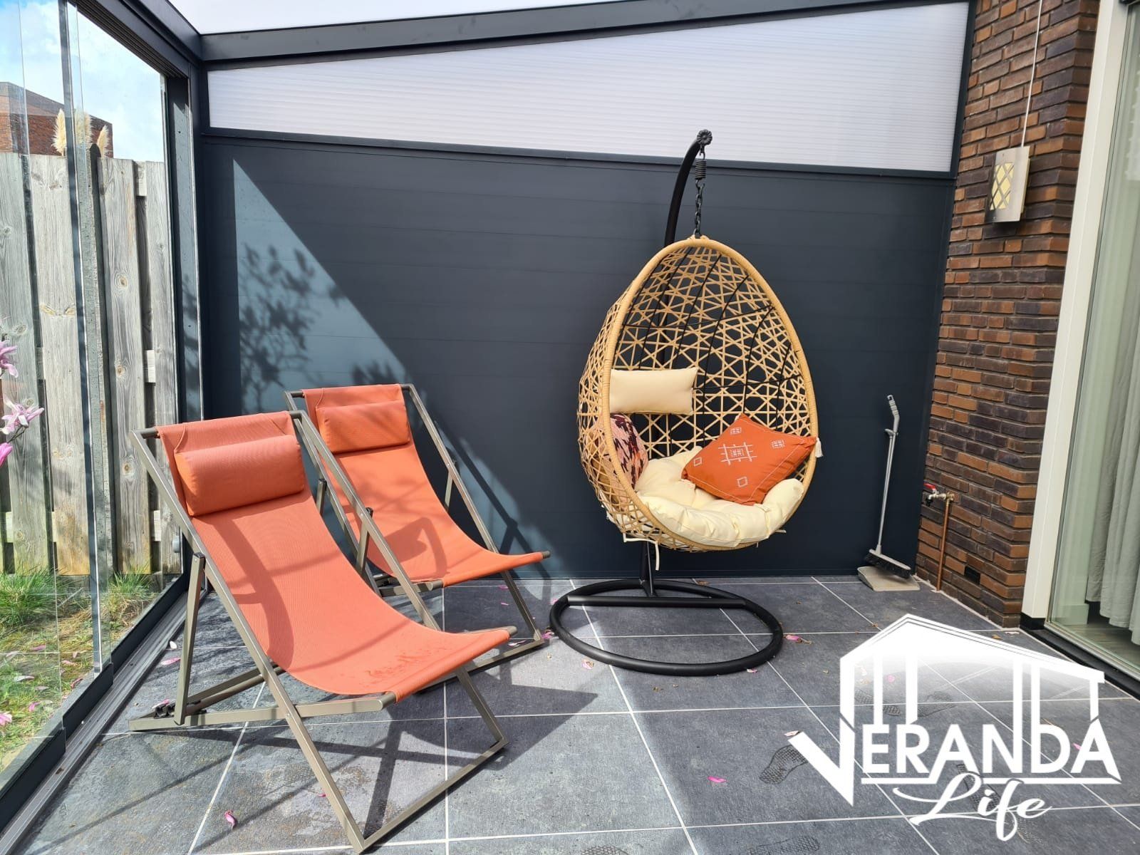 Twee stoelen en een hangstoel in een veranda met verandaleven op de onderkant geschreven