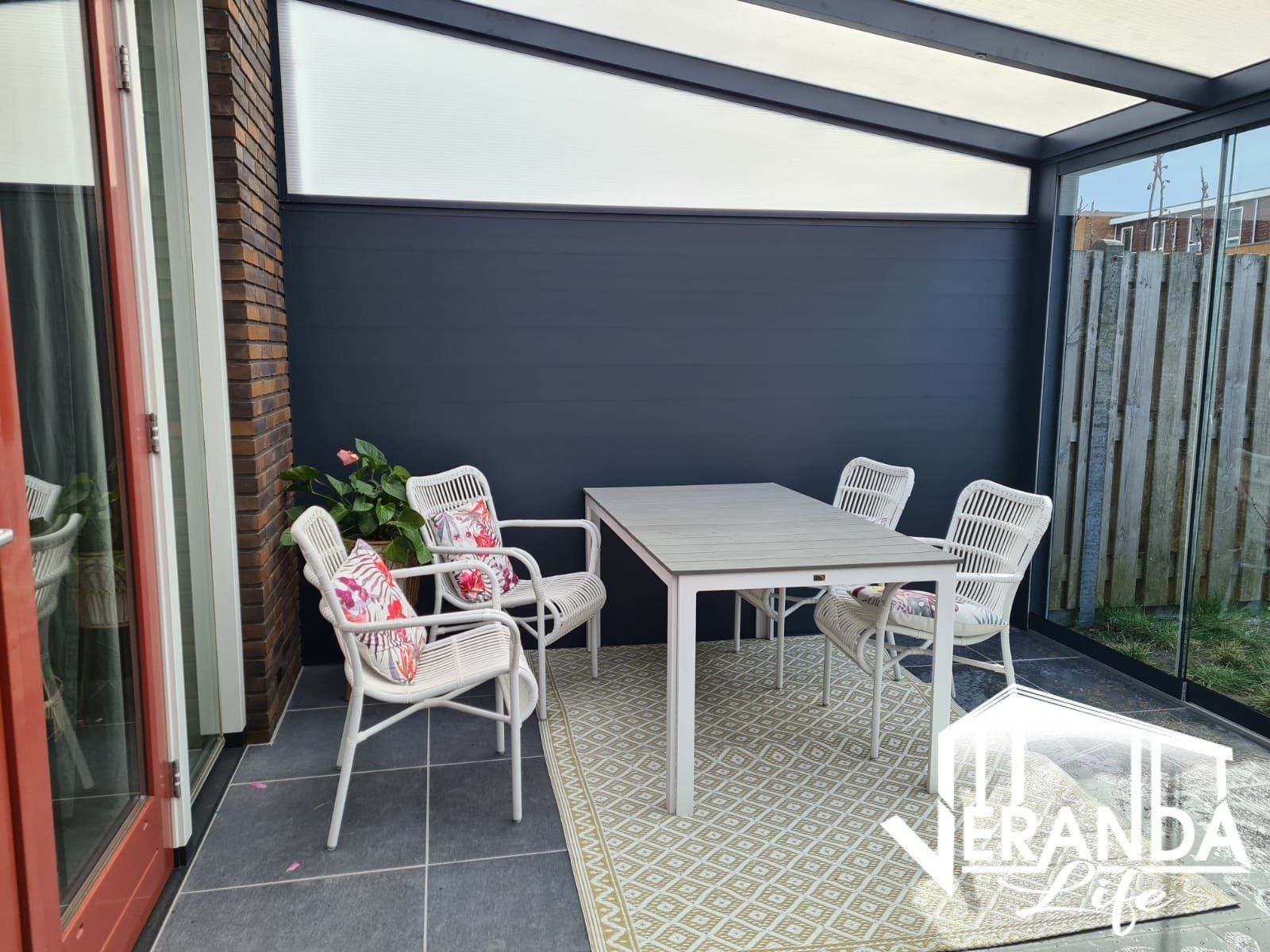 Een patio met een tafel en stoelen in een veranda