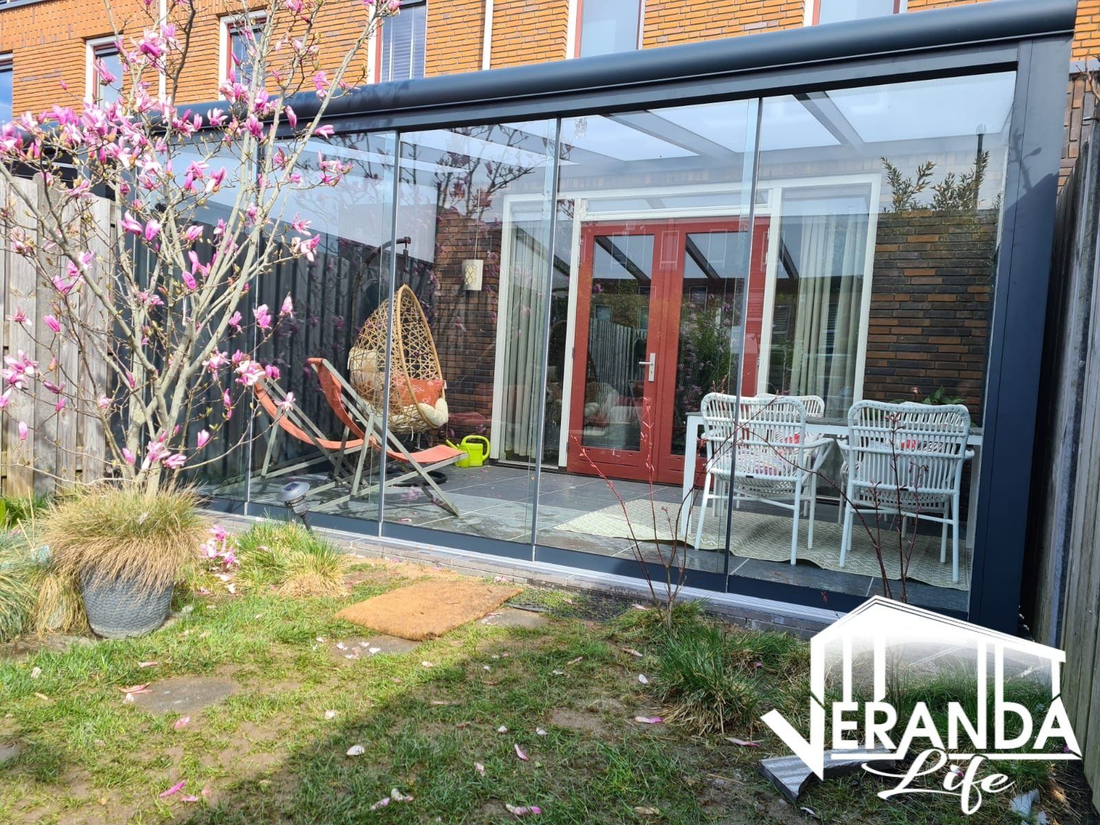 Een veranda met glazen schuifdeuren en een patio in de achtertuin van een huis.